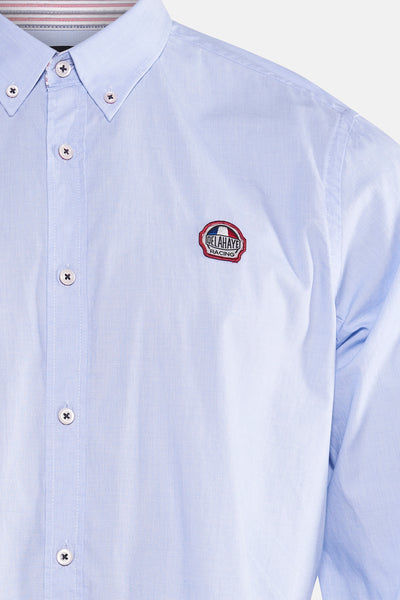 Chemise bleue de DELAHAYE avec un logo brodé sur la poitrine et une boutonnière visible.