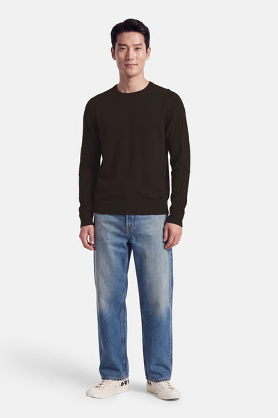 Pull col rond brun par DELAHAYE, manches à nervures, porté avec jeans délavés et baskets blanches, vue de face