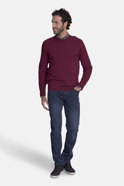Pull col rond bordeaux de DELAHAYE, porté avec un jean bleu et des baskets noires.