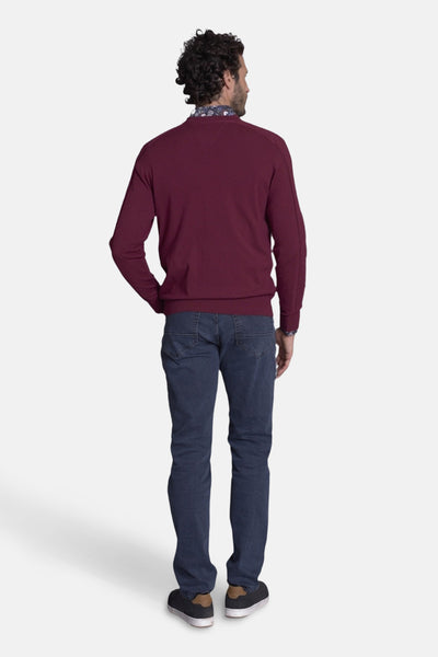 Pull col O bordeaux de DELAHAYE, porté avec une chemise à motif floral et un jean bleu foncé.