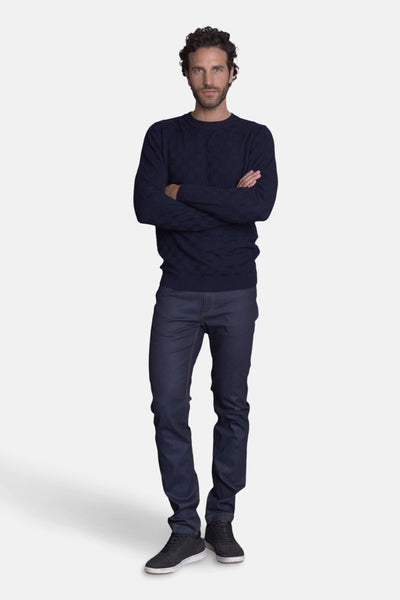Polo bleu par DELAHAYE, porté avec un pull bleu foncé, un pantalon de toile bleu marine et des chaussures de sport noires.