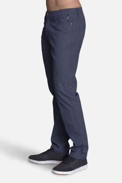 Pantalon bleu de DELAHAYE, coupe classique, porté avec des baskets noires à semelle blanche.