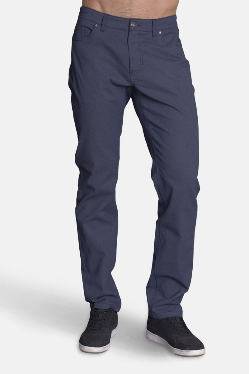 Pantalon bleu de DELAHAYE, coupe classique, porté avec des baskets noires.