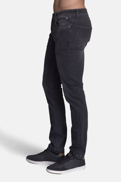 Jean slim en denim gris foncé de DELAHAYE, porté avec des baskets noires à semelles blanches, en vue latérale.
