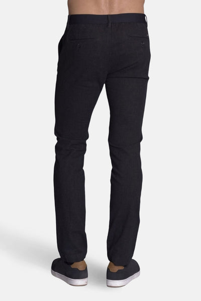 Pantalon noir par DELAHAYE, avec poches boutonnées à l'arrière et chaussures décontractées.