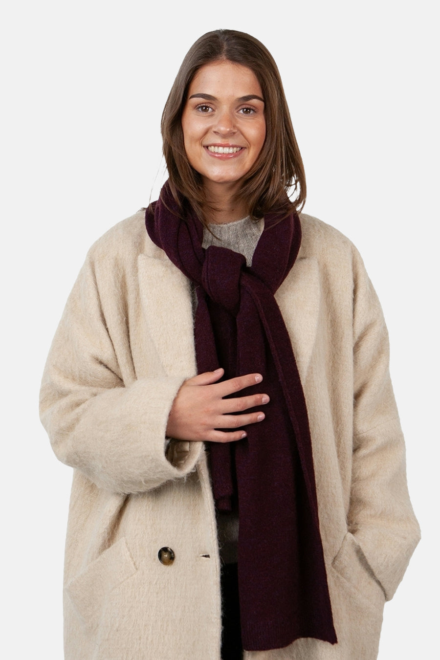 Écharpe rouge bordeaux de BARTS, nouée autour du cou, portée avec un manteau beige texturé.