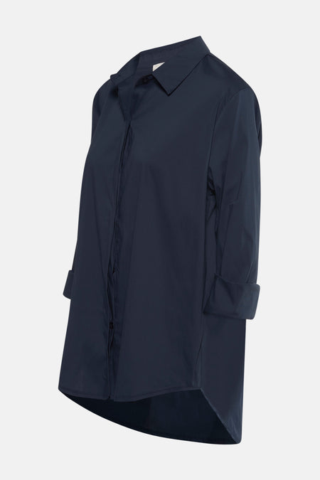 Chemise à manches longues bleue de Terra di Siena, avec manches retroussées et ourlet asymétrique visible.