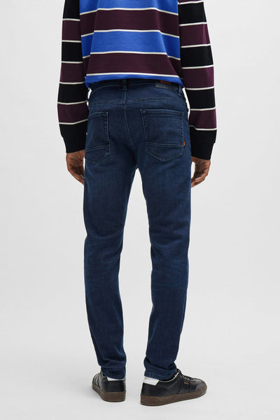 Jean fuselé en denim bleu de BOSS ORANGE, porté avec un pull à rayures.