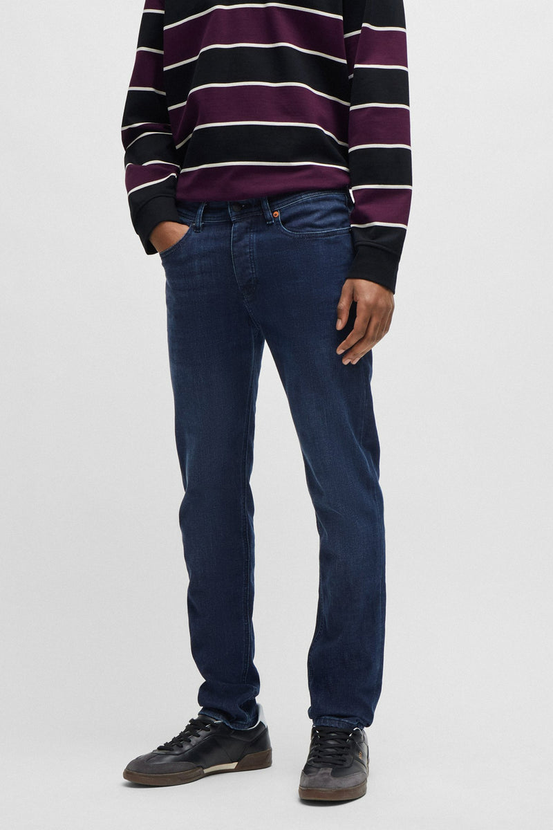 Jean fuselé en denim bleu, de BOSS ORANGE, porté avec un pull rayé.
