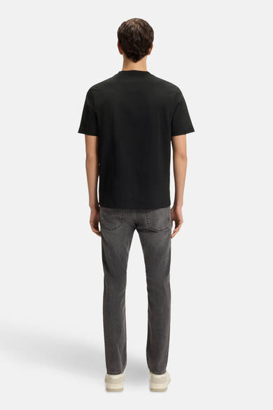 T-shirt noir à manches courtes de BOSS ORANGE, porté avec un jean gris et des chaussures beiges, vue de dos.