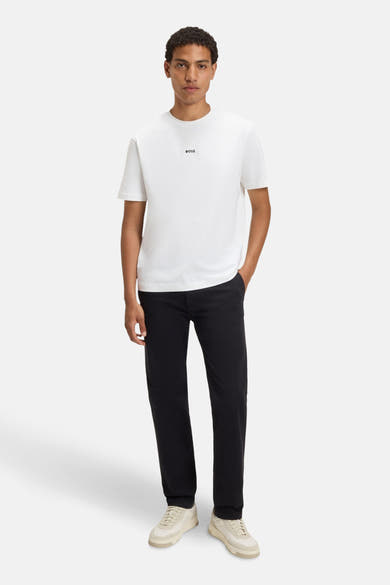T-shirt blanc à manches courtes de BOSS ORANGE, avec un logo discret, porté avec un pantalon noir et des baskets claires.