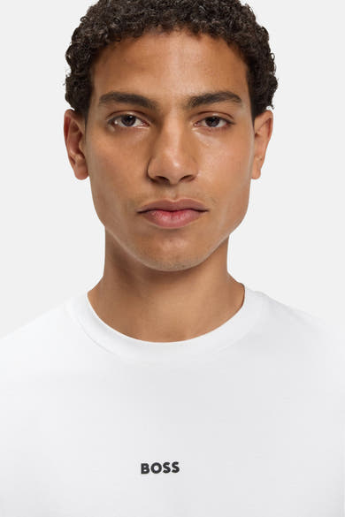 T-shirt blanc à manches courtes de BOSS ORANGE, porté par un homme à la peau bronzée.