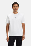 T-shirt blanc à manches courtes de BOSS ORANGE, avec un logo noir subtil sur la poitrine, porté avec un pantalon noir.
