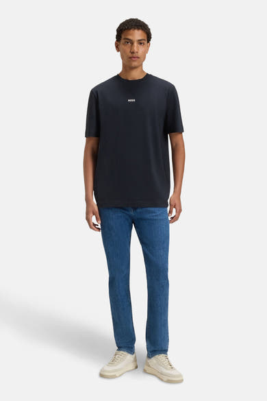 T-shirt à manches courtes bleu de BOSS ORANGE, porté avec un jean bleu et des baskets beiges