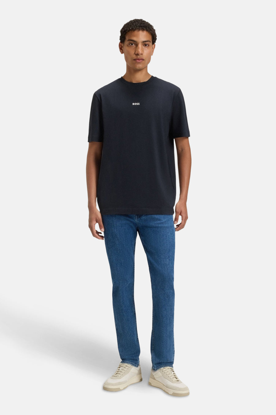 T-shirt à manches courtes bleu de BOSS ORANGE, porté avec un jean bleu et des baskets beiges