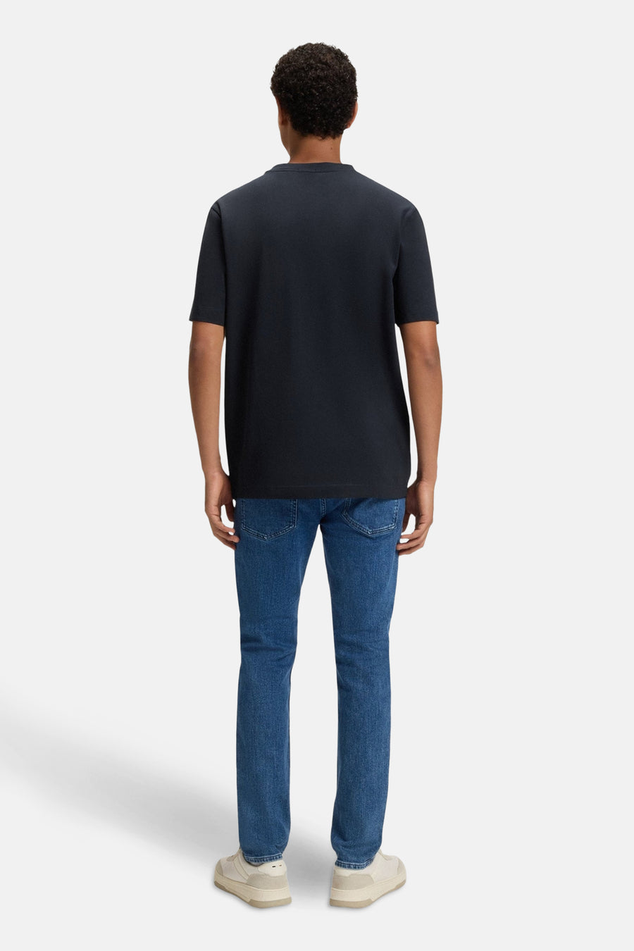 T-shirt bleu à manches courtes de BOSS ORANGE, porté avec un jean bleu et des chaussures beiges, vue de dos.
