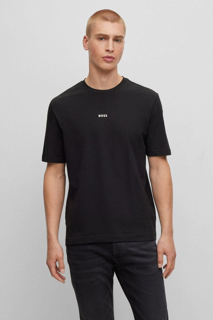 T-shirt à manches courtes noir de BOSS, avec le logo blanc sur la poitrine, porté avec un jean foncé.
