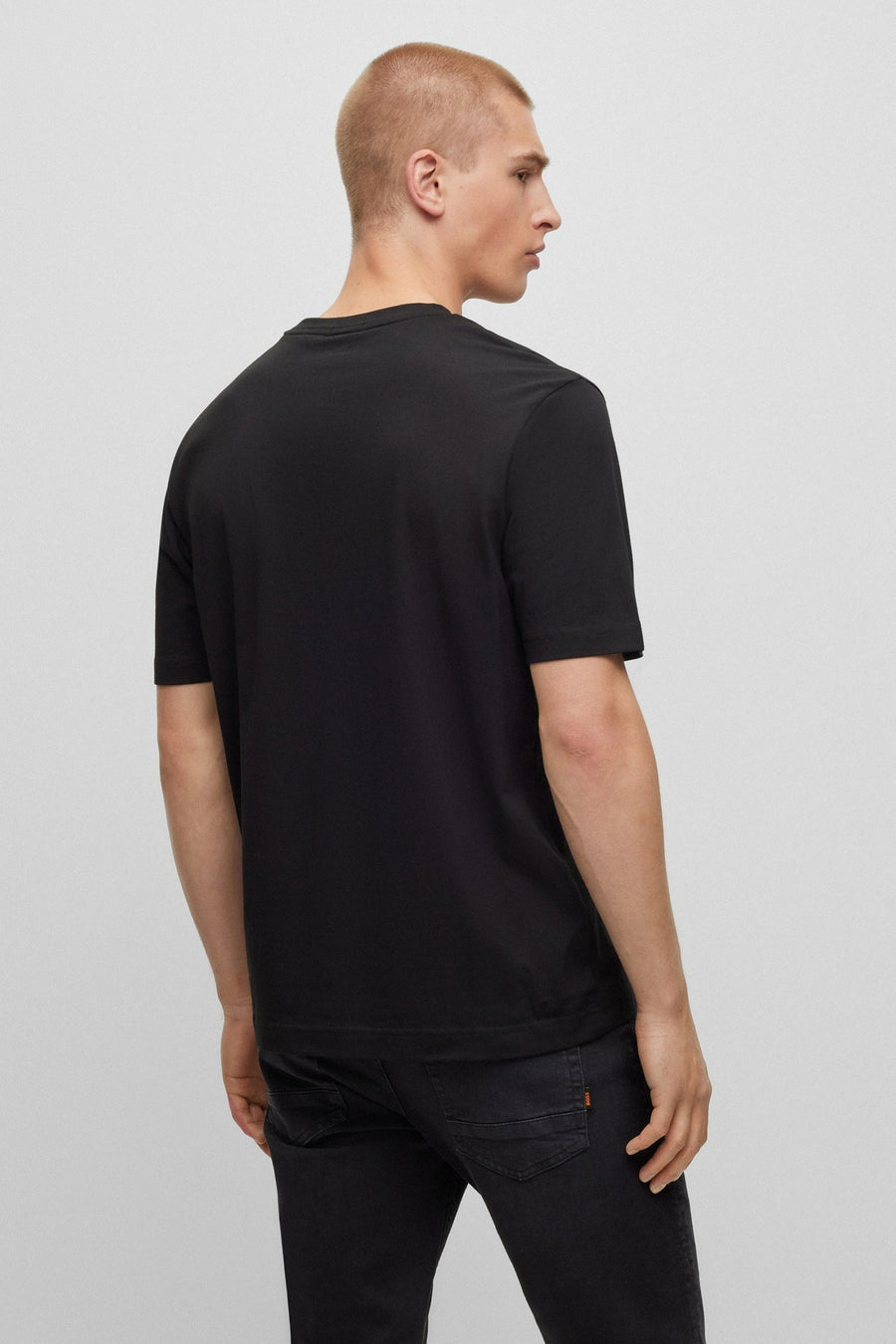 T-shirt bleu à manches courtes de BOSS ORANGE, porté avec un jean noir, vue de dos.
