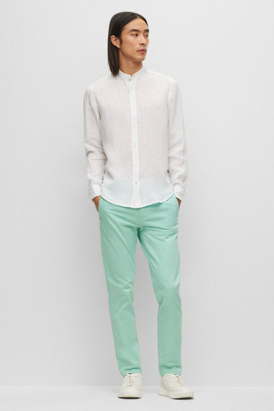 Chemise blanche à manches longues de BOSS ORANGE, portée avec un pantalon vert d'eau et des baskets blanches.