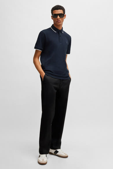 Polo bleu marine à bordures blanches de BOSS, porté avec un pantalon noir et des baskets.