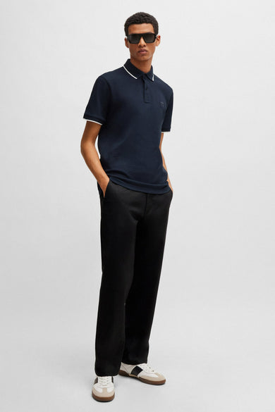 Polo bleu marine à bordures blanches de BOSS, porté avec un pantalon noir et des baskets.