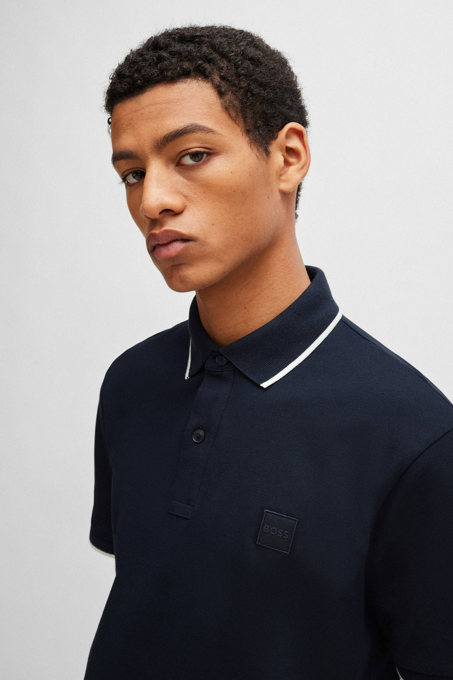 Polo bleu marine par BOSS, col et manches bordés de blanc, logo carré ton sur ton.