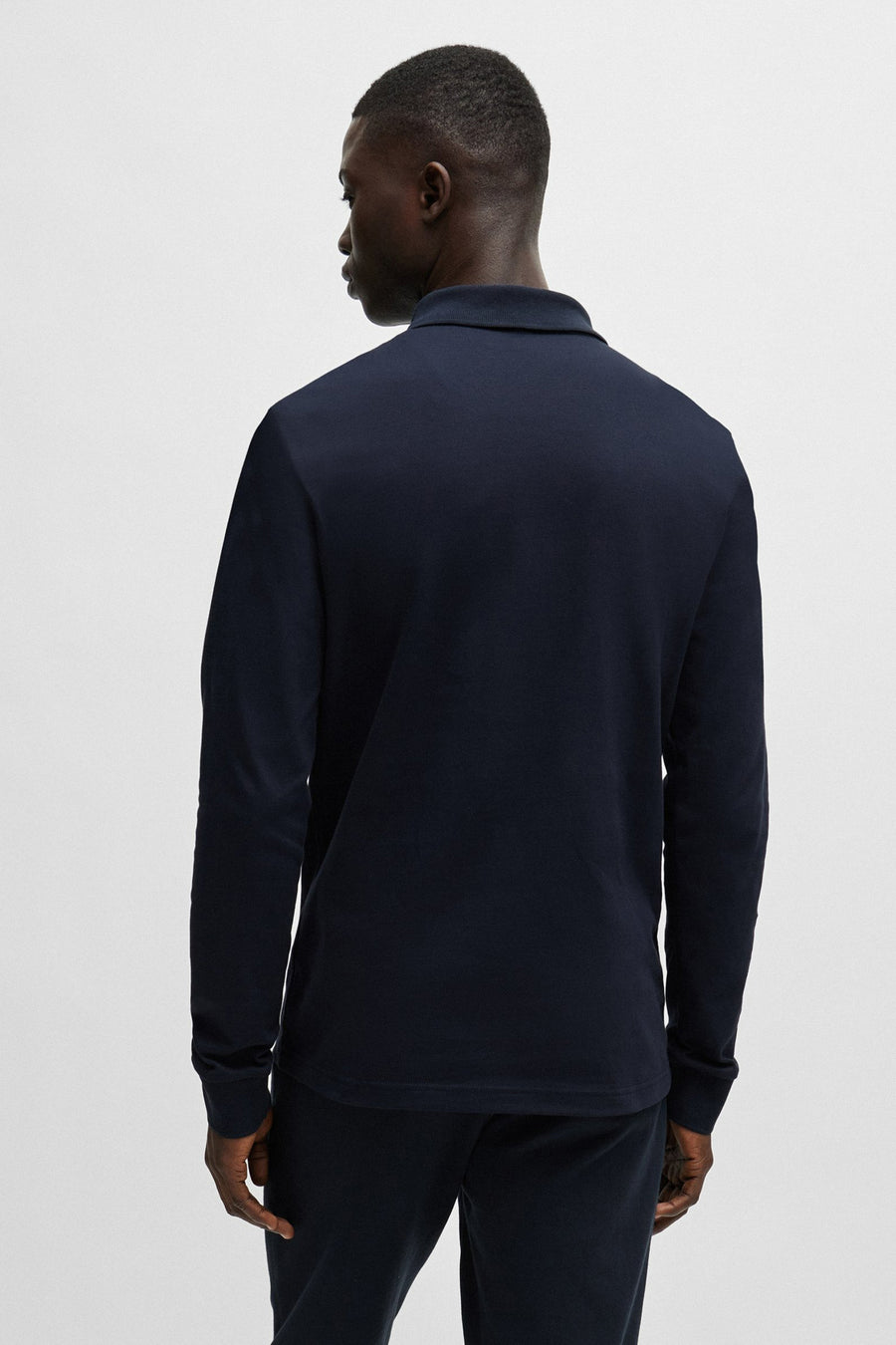 Polo bleu marine de BOSS ORANGE, montrant le dos, porté avec un pantalon assorti.