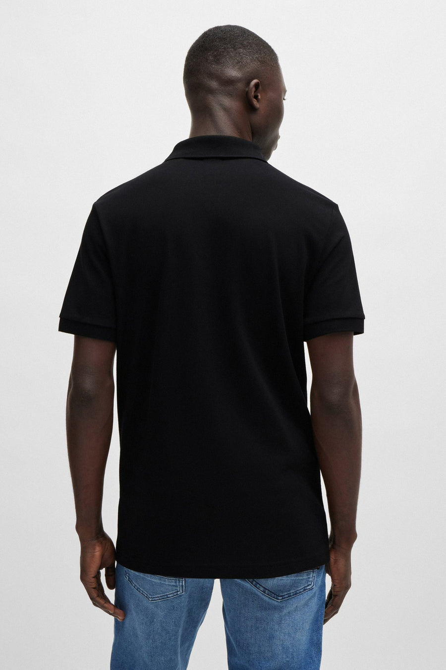 Zwart poloshirt met korte mouwen van BOSS ORANGE, achterkant, gedragen met een blauwe spijkerbroek.