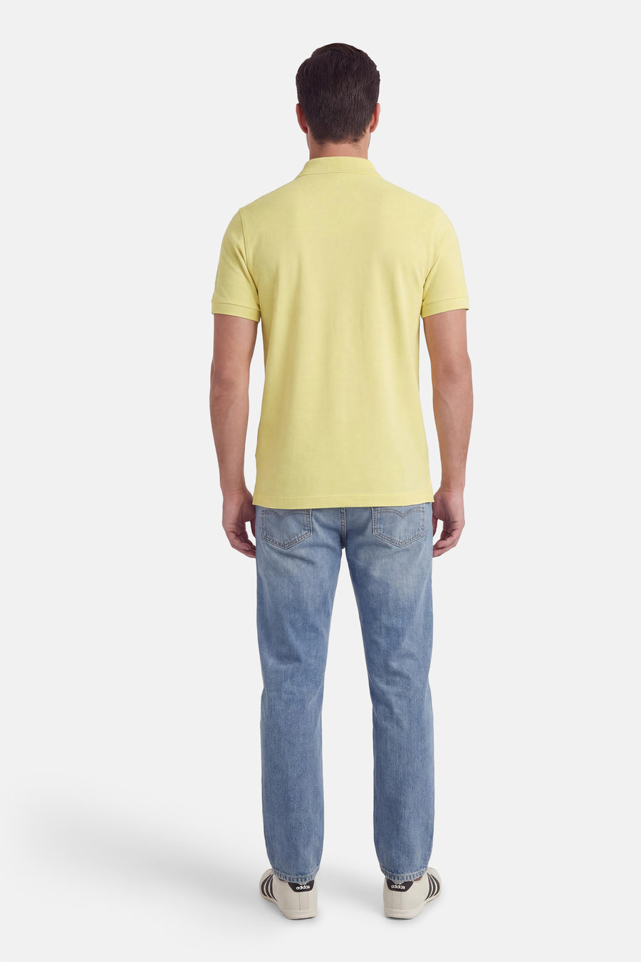 Polo vert de BOSS ORANGE, porté avec un jean bleu et des baskets blanches, vue de dos.