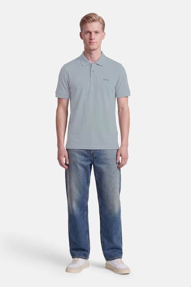 Polo gris à manches courtes de BOSS ORANGE, col boutonné, logo discret sur poitrine, porté avec jeans délavés et baskets blanches, vue frontale.