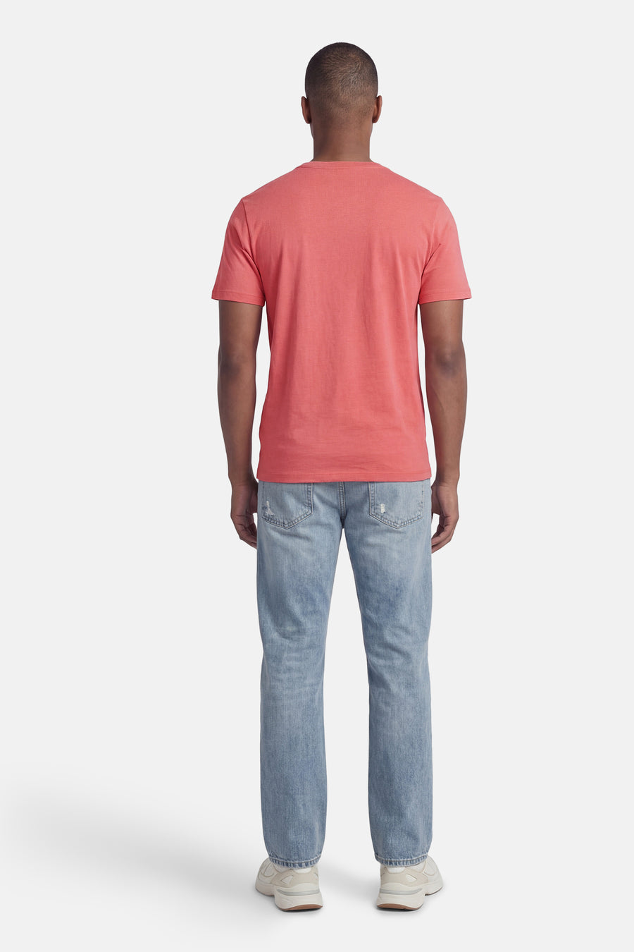 T-shirt rose de BOSS ORANGE, à manches courtes, porté de dos avec un jean clair et des baskets.