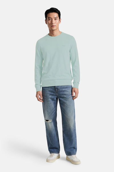 Turquoise crewneck sweater by BOSS, ribbed cuffs and hem, worn with distressed jeans and white sneakers, full-length front view