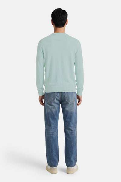 Turquoise crewneck sweater back view, ribbed cuffs and hem, worn with blue jeans and white sneakers