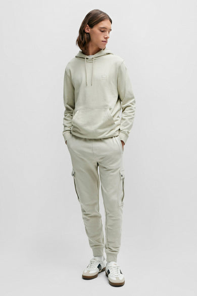 Beige hoodie van BOSS ORANGE, gedragen met een aangepaste cargo broek en sportbaskets.