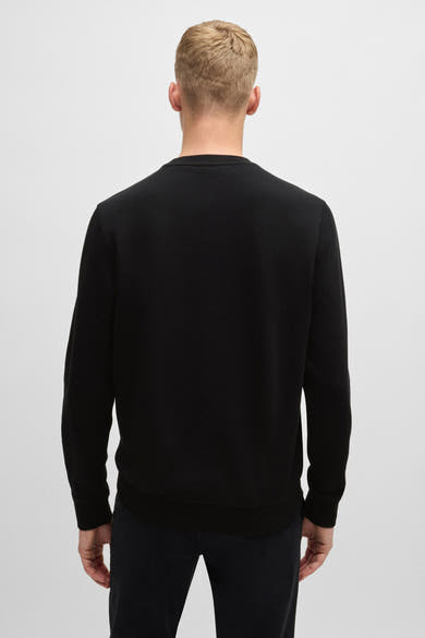 Sweat-shirt noir col rond de BOSS ORANGE, porté avec un pantalon noir, vue de dos.

