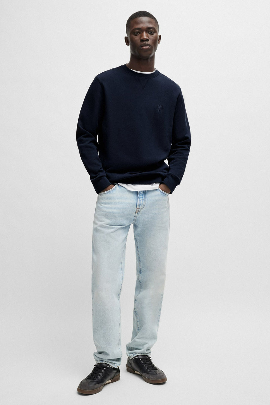 Sweat bleu de BOSS ORANGE, porté avec un jean clair et des baskets foncées.