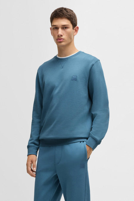 Ronde hals sweatshirt blauw van BOSS ORANGE, gedragen met een bijpassende joggingbroek, op een effen achtergrond.