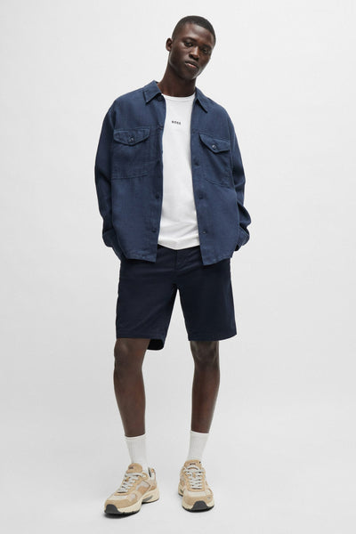 Bermuda bleu de BOSS ORANGE, porté avec un t-shirt blanc et une surchemise bleu marine.