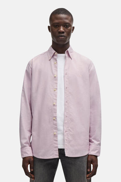 Chemise rose à manches longues de BOSS ORANGE, portée ouverte sur un t-shirt blanc, avec boutons et ourlet droit.