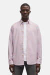 Chemise rose à manches longues de BOSS ORANGE, portée ouverte sur un t-shirt blanc, avec boutons et ourlet droit.