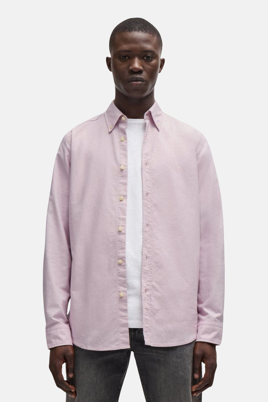 Chemise rose à manches longues de BOSS ORANGE, portée ouverte sur un t-shirt blanc, avec boutons et ourlet droit.