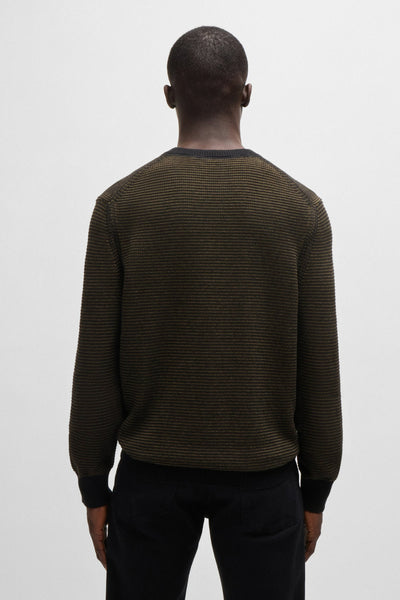 Pull noir à col rond de BOSS ORANGE, texture tricotée à rayures horizontales, porté avec un pantalon noir.