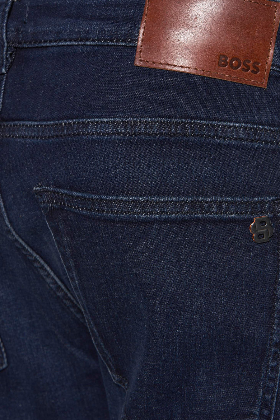 Jean slim en denim bleu foncé de BOSS ORANGE avec étiquette en cuir et logo métallique sur la poche.