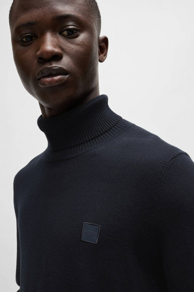 Pull à col roulé bleu de BOSS, avec un logo discret sur la poitrine et une texture côtelée au col.
