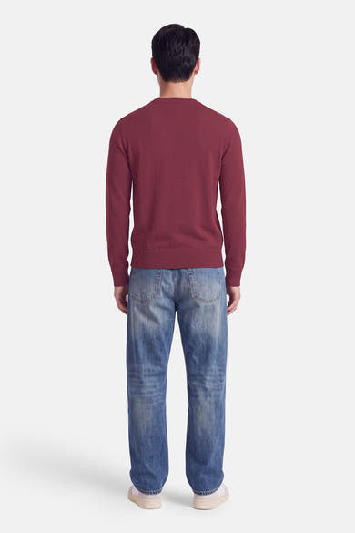 Pull col rond rouge de BOSS ORANGE, vue arrière, en maille fine, porté avec un jean délavé et des baskets blanches