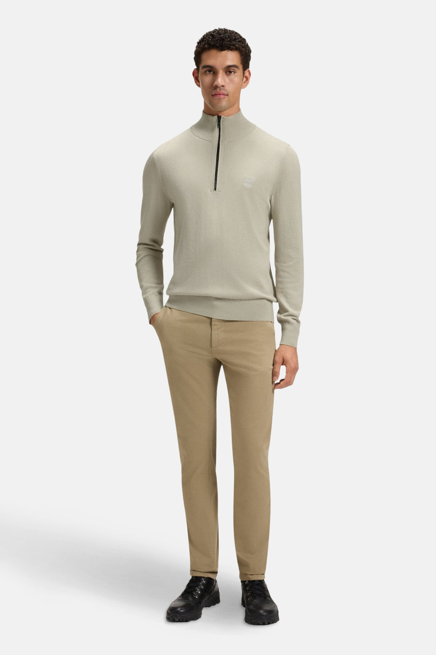 Pull col roulé gris par BOSS ORANGE, avec fermeture éclair et porté avec un pantalon chino beige et des chaussures noires.
