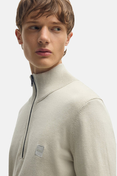 Pull à col roulé beige de BOSS, avec fermeture éclair courte et logo discret sur le devant.
