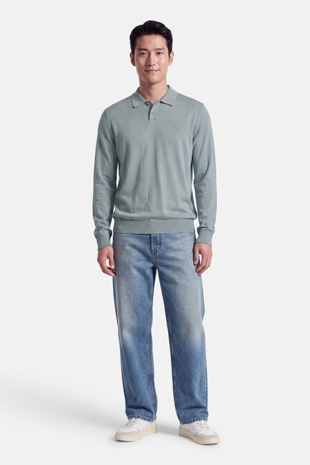 Pull gris à col polo de BOSS ORANGE, coupe ajustée, avec logo discret sur poitrine, porté avec jeans délavés et baskets blanches, vue frontale.
