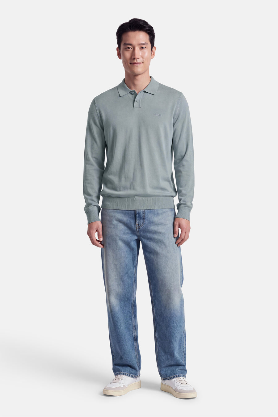 Pull gris à col polo de BOSS ORANGE, coupe ajustée, avec logo discret sur poitrine, porté avec jeans délavés et baskets blanches, vue frontale.