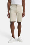 Short beige de BOSS ORANGE, porté avec un t-shirt blanc et des baskets blanches.